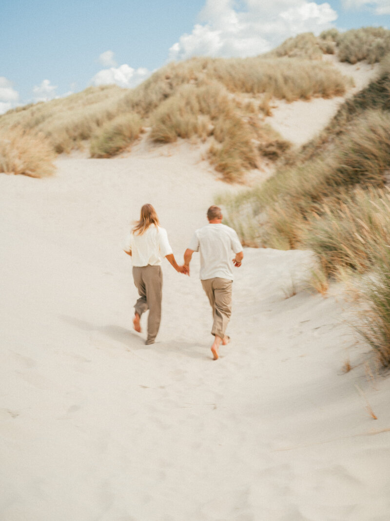 Stel dat hand in hand door het zand en de duinen rent.